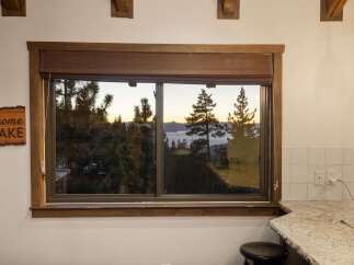 Enjoy breathtaking lake views from this stunning property, framed by a rustic wooden window.