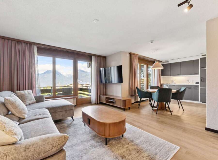 Experience breathtaking mountain views from this stunning living area, featuring a plush sectional sofa and a modern entertainment center.