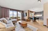 Experience breathtaking mountain views from this stunning living area, featuring a plush sectional sofa and a modern entertainment center.