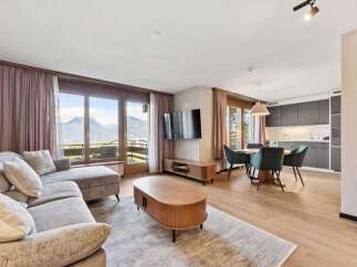 Experience breathtaking mountain views from this stunning living area, featuring a plush sectional sofa and a modern entertainment center.