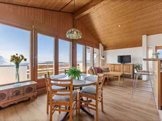 Experience breathtaking mountain views from this charming dining area, featuring a round table with four chairs and a large window overlooking the scenic landscape.