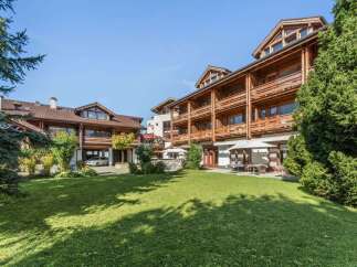 Experience alpine charm in this stunning property featuring a multi-story wooden building with balconies and a well-maintained lawn.