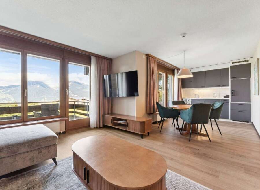 Experience breathtaking mountain views from this stunning living space, featuring a modern open-plan kitchen and a cozy dining area perfect for entertaining.