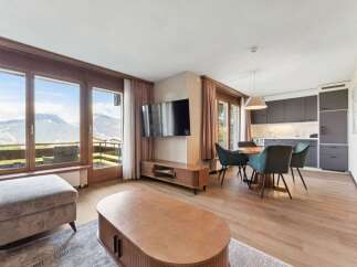 Experience breathtaking mountain views from this stunning living space, featuring a modern open-plan kitchen and a cozy dining area perfect for entertaining.