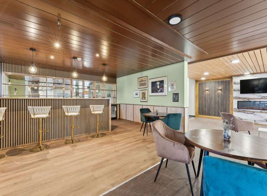 Step into a sophisticated lounge area featuring a sleek bar with plush seating and elegant pendant lighting.