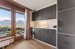 Experience stunning mountain views from this modern kitchen, featuring sleek dark cabinetry and a convenient balcony access.