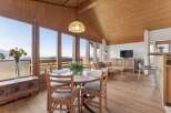 Experience breathtaking mountain views from this stunning dining and living area, featuring a charming wooden ceiling and expansive windows.
