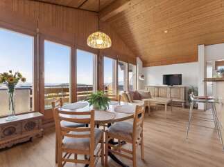 Experience breathtaking mountain views from this stunning dining and living area, featuring a charming wooden ceiling and expansive windows.
