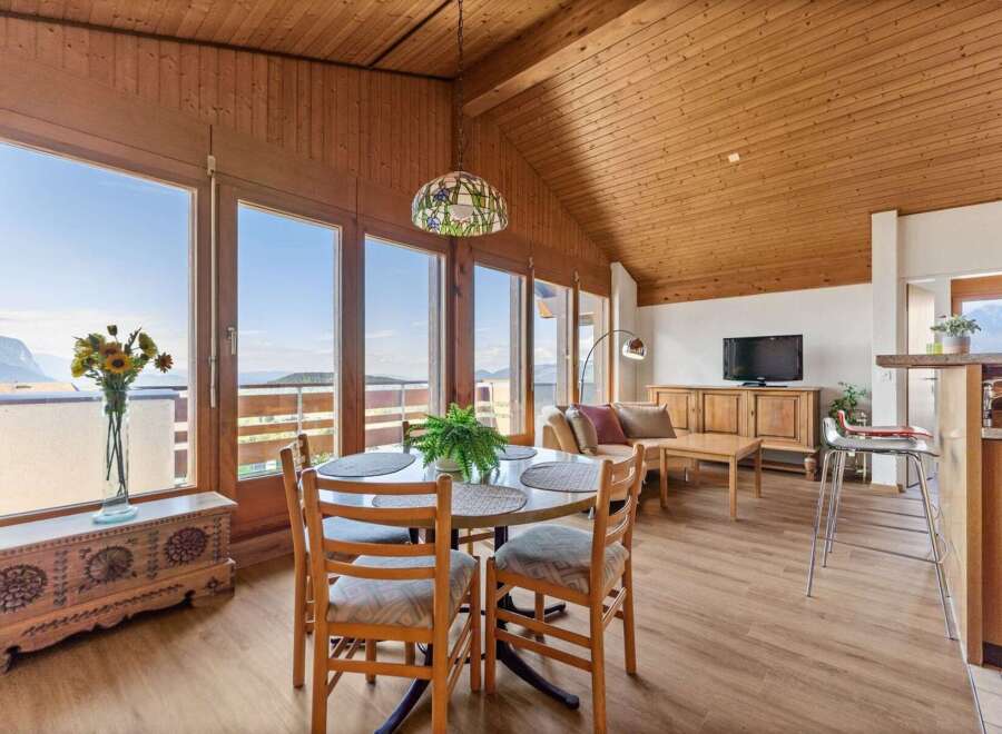 Experience breathtaking mountain views from this charming dining area, featuring a round table with four chairs and a large window overlooking the scenic landscape.