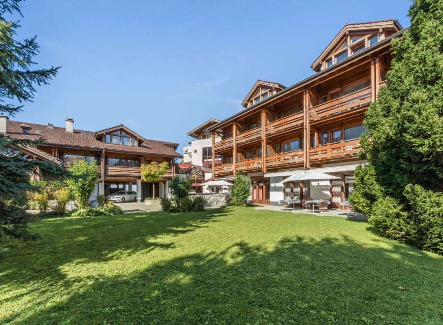 Experience alpine charm in this stunning property featuring a multi-story wooden building with balconies and a well-maintained lawn.