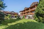 Experience alpine charm in this stunning property featuring a multi-story wooden building with balconies and a well-maintained lawn.