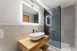 Experience modern luxury in this stunning bathroom featuring a sleek vessel sink atop a warm wooden vanity.