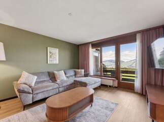 Experience breathtaking mountain views from this stunning living room, featuring a plush sectional sofa perfect for relaxation.
