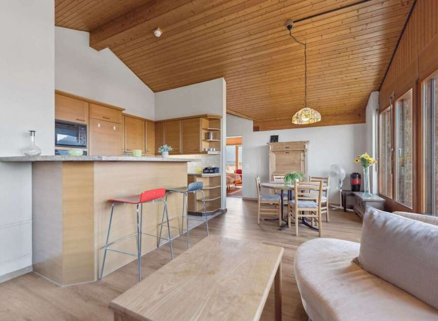 Experience modern living in this open-concept space featuring a sleek kitchen with ample cabinetry and a breakfast bar, perfect for casual dining.