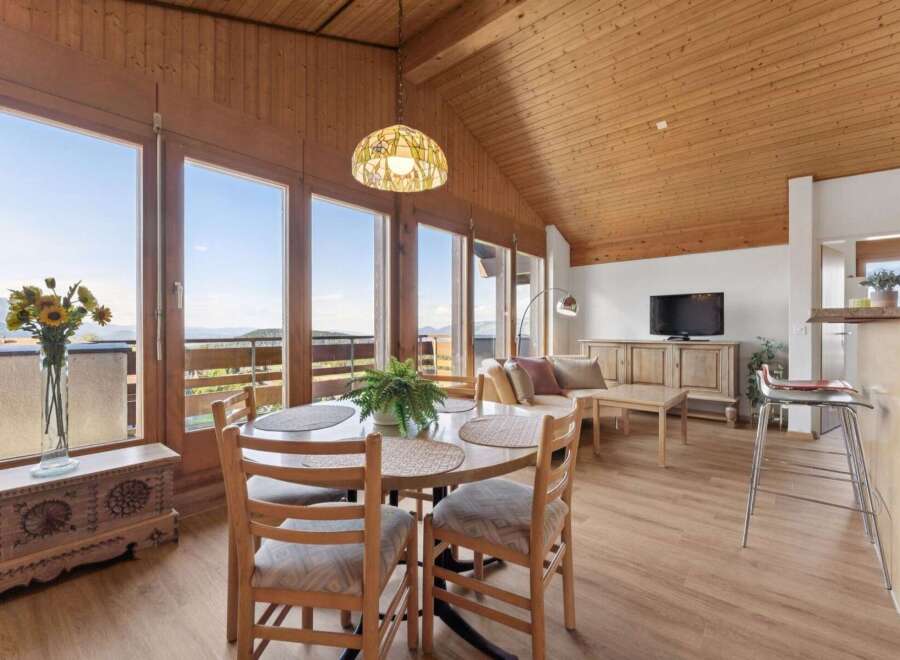 Experience breathtaking mountain views from this stunning dining and living area, featuring a charming wooden ceiling and expansive windows.