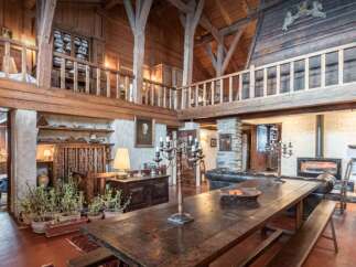 Experience rustic charm in this expansive living space, featuring a grand wooden dining table and benches perfect for gatherings.