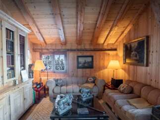 Experience rustic charm in this cozy living room, featuring exposed wooden beams and paneled walls that create a warm, inviting atmosphere.