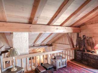 Experience rustic charm in this loft space featuring exposed wooden beams and a sloped ceiling, creating a cozy and inviting atmosphere.