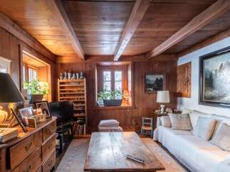 Step into a rustic mountain retreat with this charming living room, featuring warm wood paneling and exposed beams that create a cozy, inviting atmosphere.