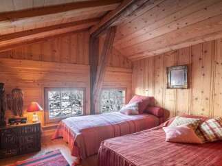 Experience rustic charm in this cozy attic bedroom, featuring exposed wooden beams and warm wood paneling throughout.