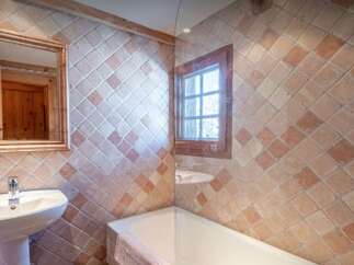 This charming bathroom features rustic terracotta tiles on the walls, creating a warm and inviting atmosphere.