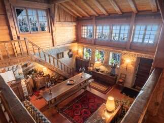 Experience rustic charm in this stunning multi-level log cabin featuring a grand dining area with a long wooden table and benches, perfect for gatherings.