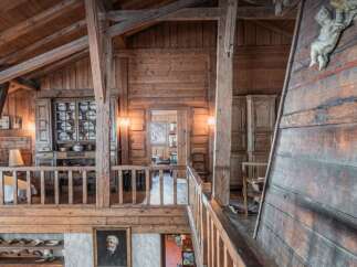 Experience rustic charm in this stunning wooden interior, featuring exposed beams and a cozy loft overlooking a living area.
