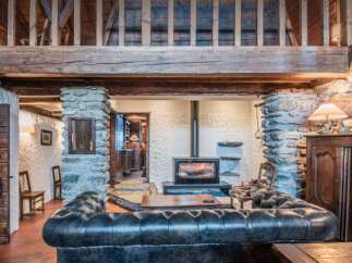 Experience rustic charm in this cozy living room featuring a modern wood-burning stove set against a textured stone wall.