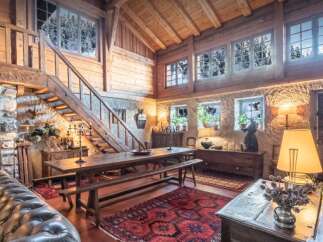 Experience rustic charm in this spacious log cabin living area, featuring a grand wooden dining table with benches, perfect for family gatherings.