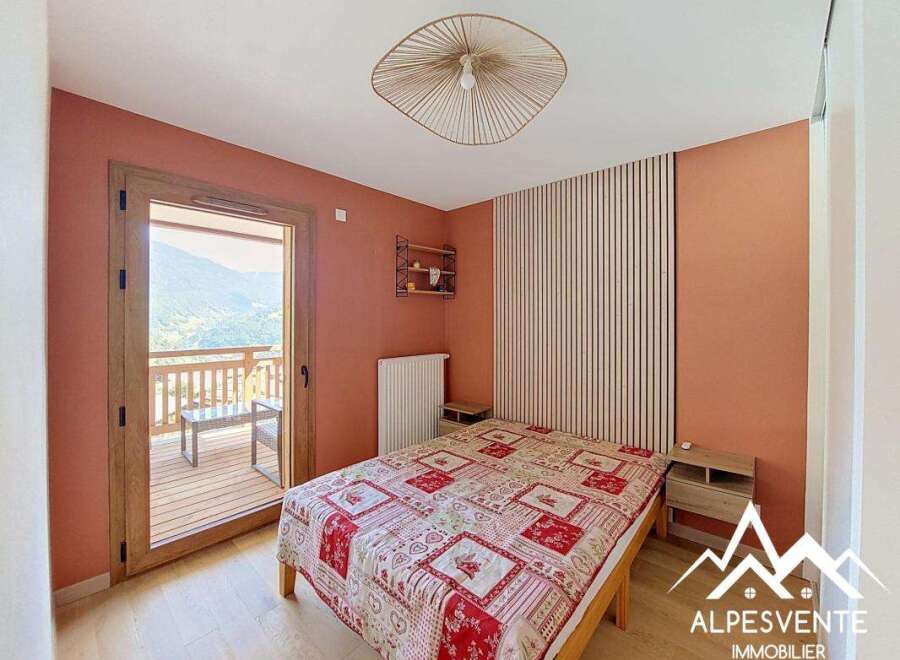 Experience breathtaking mountain views from this charming bedroom, featuring a cozy bed with a vibrant red and white patterned comforter.