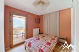 Experience breathtaking mountain views from this charming bedroom, featuring a cozy bed with a vibrant red and white patterned comforter.