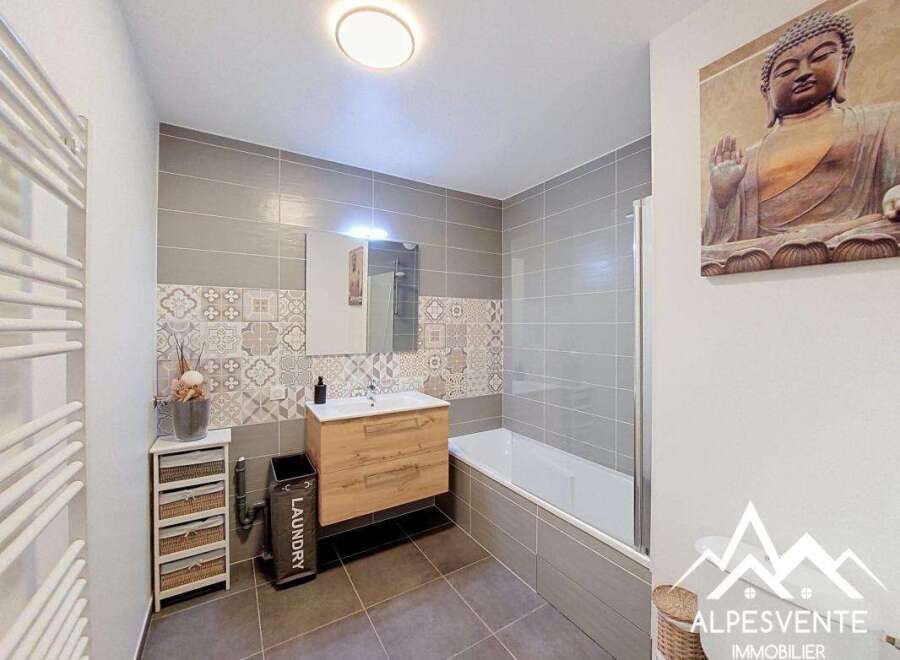 This modern bathroom features a sleek design with grey tiled walls and a decorative patterned tile accent.