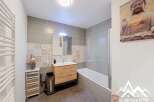 This modern bathroom features a sleek design with grey tiled walls and a decorative patterned tile accent.