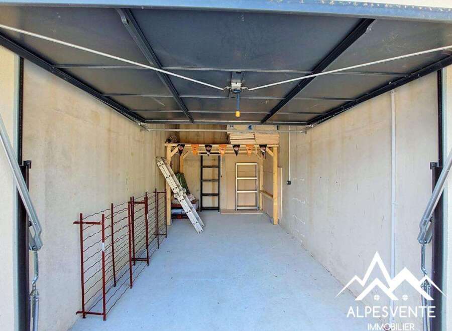 Discover ample storage and organization potential in this spacious garage, featuring a sturdy shelving unit and a convenient ladder for easy access to higher storage.