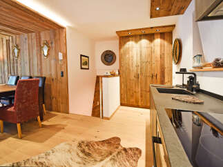 Experience rustic charm in this beautifully appointed dining and kitchen area, featuring warm wood paneling and a cozy cowhide rug.
