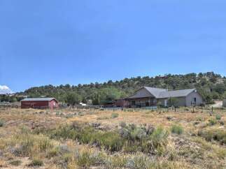 Discover this expansive property featuring a charming ranch-style home with a wraparound porch, perfect for enjoying the scenic views.