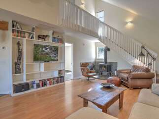 Experience cozy living in this spacious room featuring a modern wood-burning stove and a comfortable leather armchair.