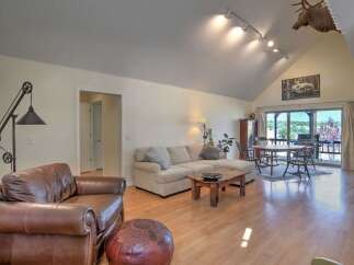 Experience rustic charm in this spacious living area, featuring a plush sectional sofa and a cozy leather armchair perfect for relaxation.