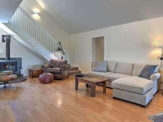 This spacious living room features a cozy fireplace, comfortable seating including a plush leather armchair and a sectional sofa, and a rustic wooden coffee table.