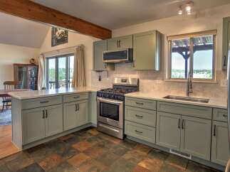 Discover this charming kitchen featuring sage green cabinetry and sleek marble countertops.