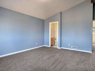 Discover comfort and style in this spacious room featuring calming blue walls and plush carpeting.