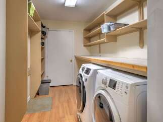This spacious laundry room offers ample storage with built-in shelving and a convenient countertop space.