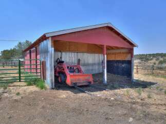 This property features a versatile red barn with a tractor and loader, perfect for agricultural needs or storage.