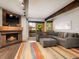 Cozy up by the stone fireplace in this inviting living room, featuring a large sectional sofa perfect for relaxing after a day on the slopes.