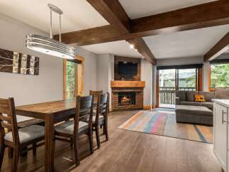 Experience cozy living in this mountain retreat, featuring a rustic stone fireplace and exposed wooden beams.