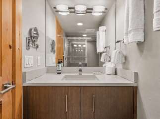 Experience modern luxury in this beautifully appointed bathroom, featuring a sleek vanity with ample counter space and warm wood cabinetry.