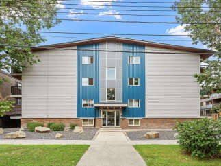Discover modern living in this multi-story apartment building featuring a striking blue and gray facade with ample windows.