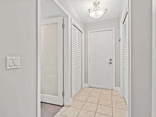 Step into this inviting hallway featuring a convenient light switch panel and a frosted glass door leading to a private space.