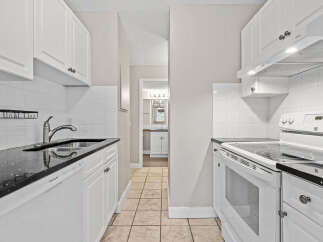 Discover this charming kitchen featuring sleek white cabinetry and durable granite countertops.