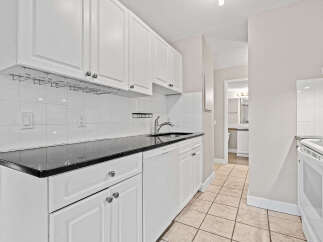 This charming kitchen features sleek white cabinetry complemented by a stunning black granite countertop.